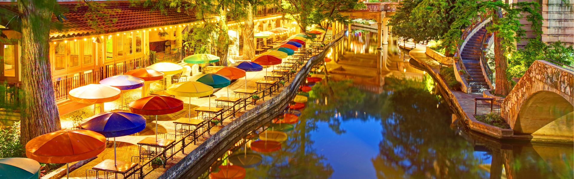 Picture of the San Antonio River Walk with outdoor tables and table umbrellas in different colors